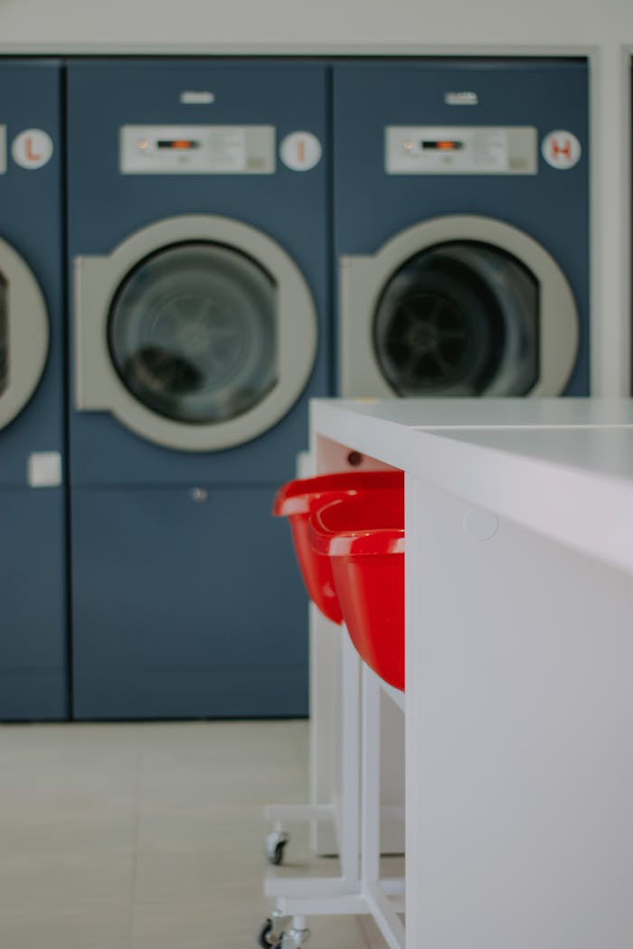 Clean and organized laundromat with blue washing machines and red laundry baskets.