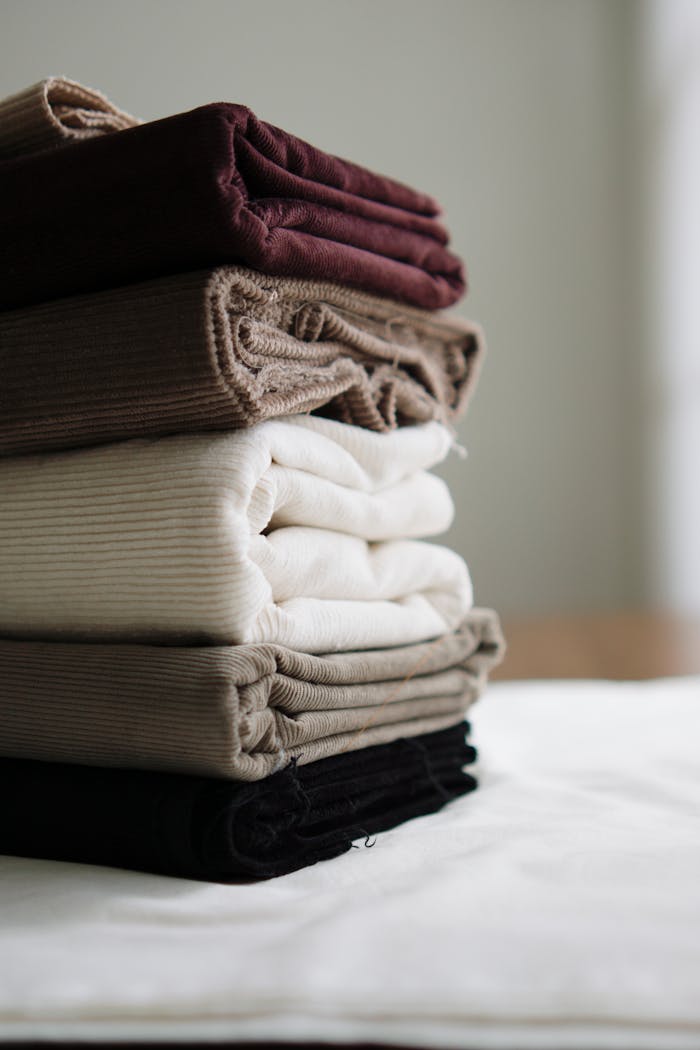 Neatly folded stack of diverse textured fabric in neutral colors for textiles and fashion use.